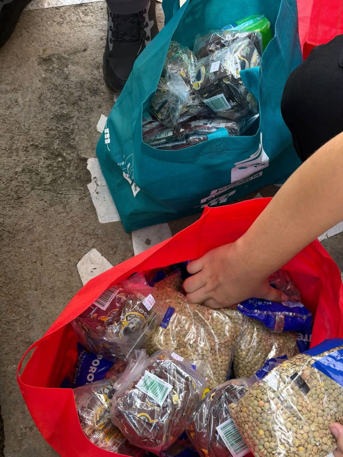 Una mano ordena víveres en bolsas para entregar a una familia